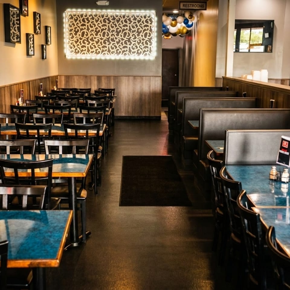 Empty restaurant dining room with rows of tables, chairs, and booths, featuring blue tabletops.